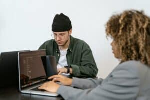 Dos personas escribiendo en ordenador portatil